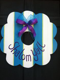 a blue and white door hanger with a purple bow