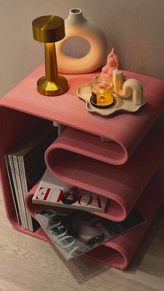 a pink shelf with magazines and vases on it