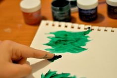 someone is doing something with green paint on paper