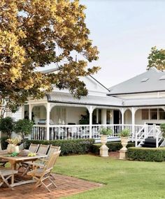 a large white house sitting on top of a lush green field next to a tree