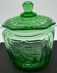 a green glass jar sitting on top of a table