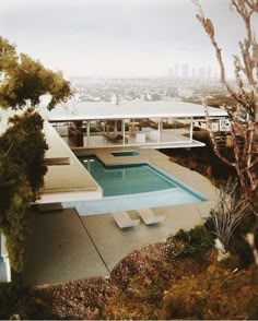 an aerial view of a house with a swimming pool in the foreground and cityscape in the background