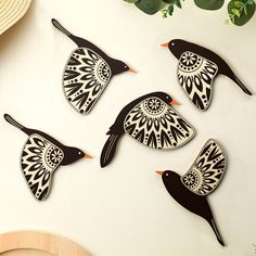 four birds are sitting on the table next to some green leaves and a straw hat