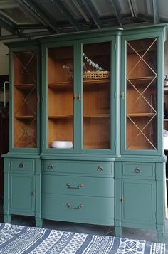 a green china cabinet with glass doors and drawers