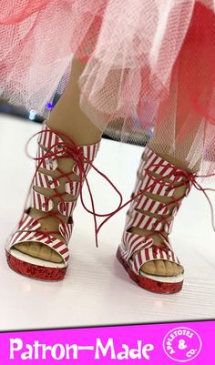 a woman's feet wearing red and white striped shoes with laces on them