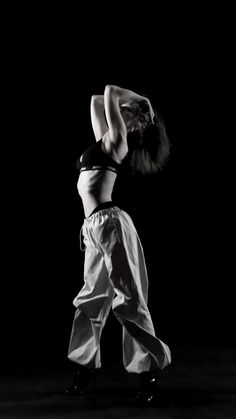 a woman is dancing in the dark with her hands behind her head and legs bent