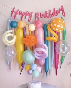 a birthday cake with balloons and streamers hanging from it's side on a table