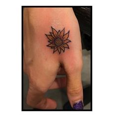 a small sunflower tattoo on the left hand