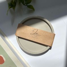 a paper tag sitting on top of a white plate next to a green leafy plant