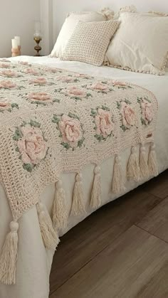 a white bed with pink flowers and tassels on it