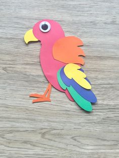 a paper cut out of a colorful bird sitting on top of a wooden table