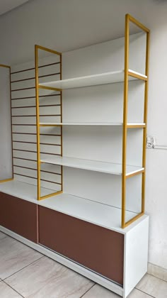 an empty white shelf with gold trim and shelves on each side, in a room