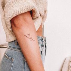 a woman's arm with a small flower tattoo on the left side of her right arm