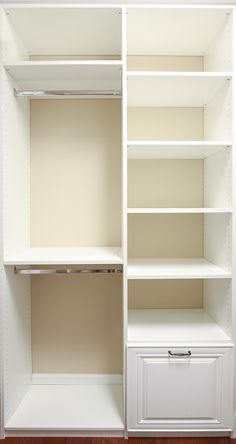 an empty closet with white shelves and drawers