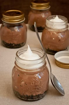 there are three jars with different types of desserts in them and one has a spoon