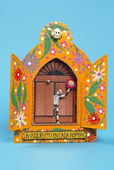 a paper cutout of a skeleton holding a flower pot in front of a door