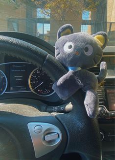 a stuffed animal sitting on the steering wheel of a car