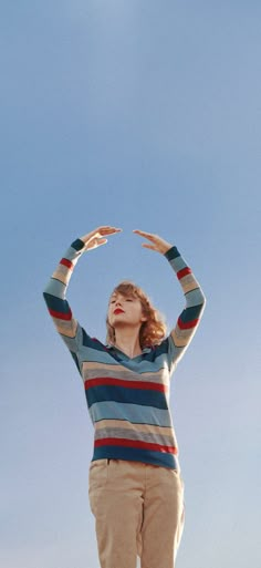 a woman standing on top of a hill with her hands in the air above her head