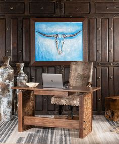 a laptop computer sitting on top of a wooden desk next to a vase and painting