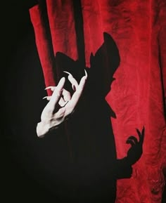 the shadow of a person's hand on a red curtain