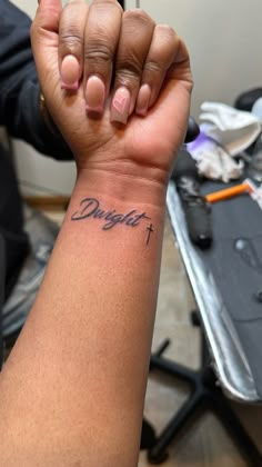 a person with a tattoo on their arm holding up the word, daughter written in cursive ink