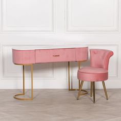 a pink desk and chair with gold legs in front of a white paneled wall