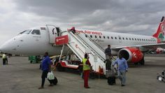 people boarding an airplane on the tarmac with their luggage and baggage handlers around them