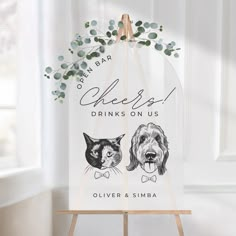 a wooden sign with two dogs on it and the words cheers drinks on us above them