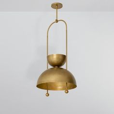 a large brass pendant light hanging from a ceiling fixture in a white room with no one around it