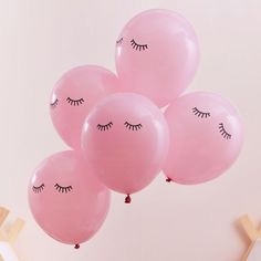 pink balloons with eyelashes on them floating in the air