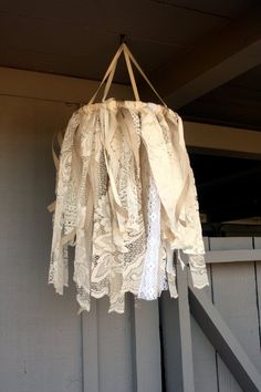 a white chandelier hanging from the side of a wooden building with lace on it