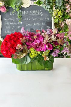 a vase filled with lots of flowers sitting on top of a table next to a chalkboard