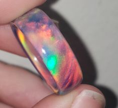 OPAREX synthetic opal is more durable and cost effective than your average opal, ensuring you will have your ring for years to come! The color shifts depending on the angle it is viewed, creating a rainbow of colors. The material is semi transparent, giving it an almost glowing effect. It is inspired by Dragon's Fire, displaying all the colors of a flame at it's hottest point. 8 mm wide This synthetic opal ring comes in a size 8 1/2 and was turned on a lathe. It is then sanded from 60 grit all t Unique Handmade Iridescent Opal Ring, Iridescent Opal Ring As A Gift, Multicolor Opal Round Ring, Iridescent Opal Ring Gift, Multicolor Opal Ring Gift, Iridescent Opal Ring Perfect For Gifts, Unique Iridescent Round Opal Ring, Handmade Iridescent Opal Ring, Iridescent Opal Ring With Unique Style