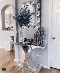 a mirrored console table with vases and mirrors on the wall in front of it