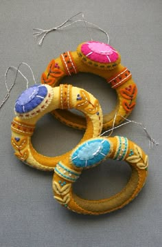 three different types of handmade rings on a gray surface with twine and thread