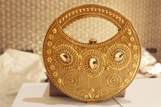 Introducing our stunning Round Gold Clutch, a must-have accessory for any special occasion. This exquisite clutch features intricate embroidery and shimmering gold beads, making it the ideal bridal handbag or bridesmaid accessory. With its elegant round design and kiss-lock closure, your belongings are kept safe while you dance the night away. Complete with a beaded strap or handle, this handbag ensures you can carry it with ease and style all night long. Elevate your ensemble with this timeless piece of luxury. Elegant Evening Bag With Gold Embroidery For Reception, Gold Festive Clutch For Festivals, Gold Embroidered Clutch For Festivals, Gold Clutch Bag With Intricate Embroidery, Gold Wedding Clutch With Zari Work, Gold Clutch With Intricate Embroidery, Gold Embroidered Clutch For Reception, Gold Clutch With Zari Work For Wedding, Elegant Evening Bag For Receptions And Festivals