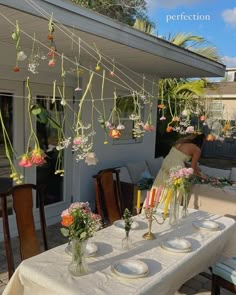 an outdoor dining area with flowers and candles hanging from the rafters over the table