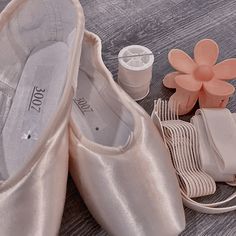 a pair of ballet shoes next to a purse and other accessories on a wooden floor