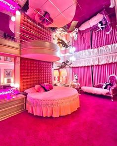 a bedroom with pink walls and carpeted flooring, large round bed in the center