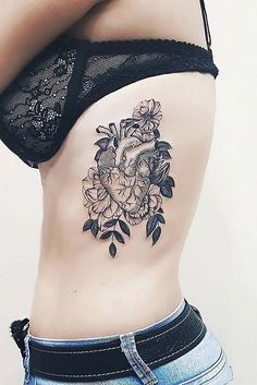 a woman's stomach with flowers and a heart tattoo on her lower back side