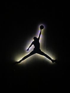 the silhouette of a basketball player jumping in the air with his arms outstretched, holding a ball