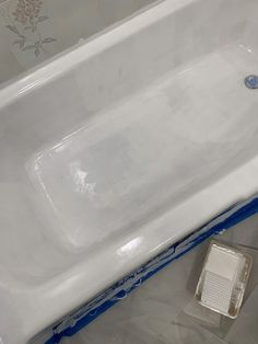 a white bath tub sitting on top of a bathroom floor next to a toilet paper dispenser