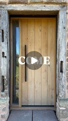 a wooden door with the word come on it in front of an old stone building