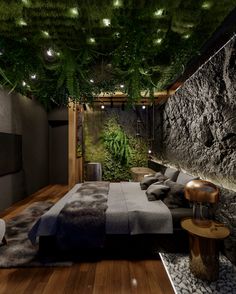 a bedroom with stone walls and plants growing on the ceiling, along with wood flooring