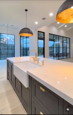 a large kitchen with an island and two lights hanging from it's ceiling over the sink