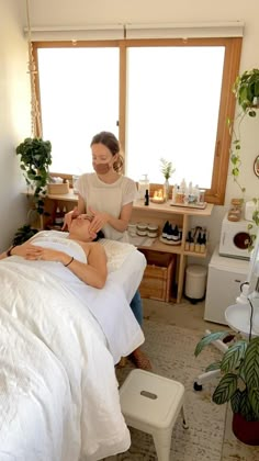 a woman getting a facial massage from a man in a room with plants on the windowsill