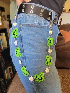 a woman is wearing a green and white beaded belt with flower decorations on it