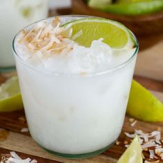 a close up of a drink on a cutting board with limes and other ingredients