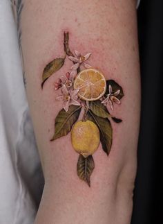 a tattoo with oranges and leaves on the side of a woman's arm