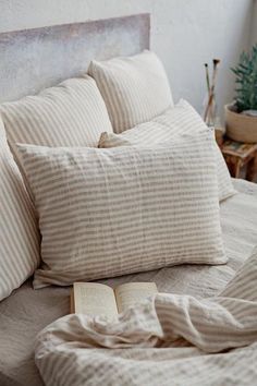 a bed with pillows and a book on top of it next to a potted plant